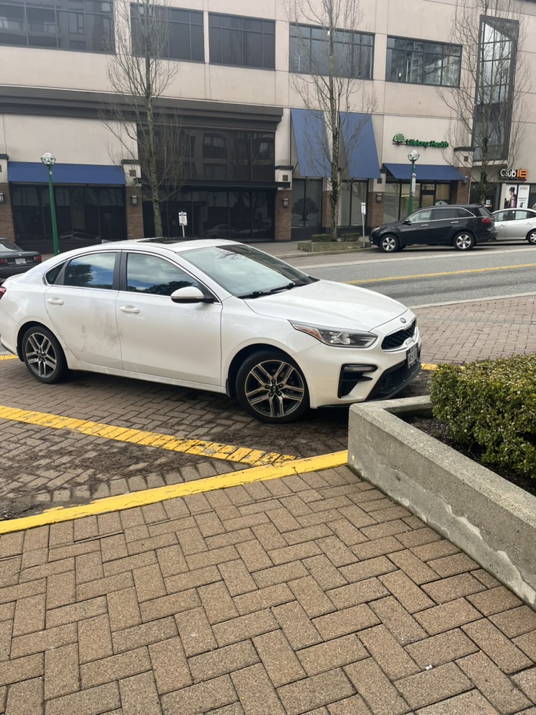 White Kia car parked on the street
